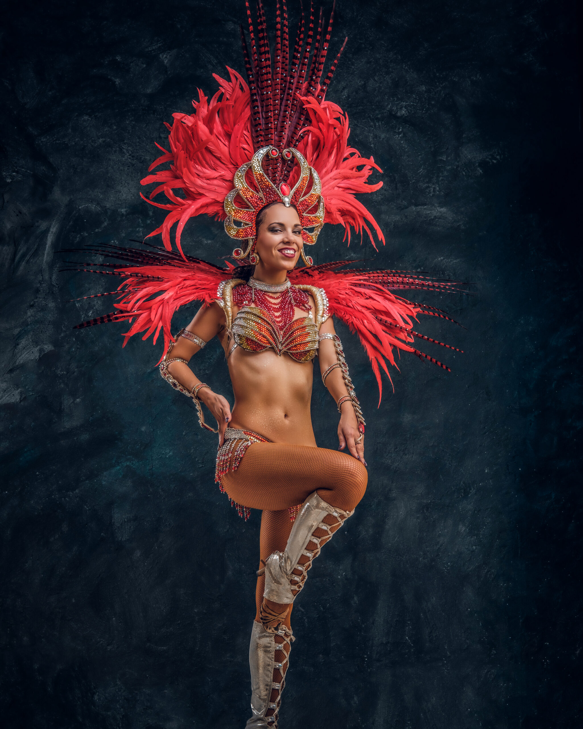 Happy beautiful brasil dancer in red feather costume is dancing on small scene.